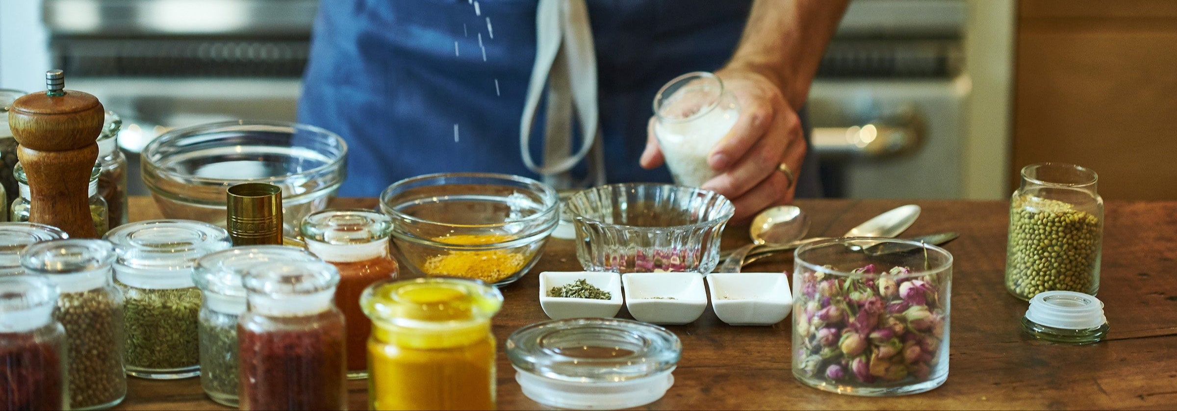 Person seasoning food with a pepper grinder in a kitchen setting