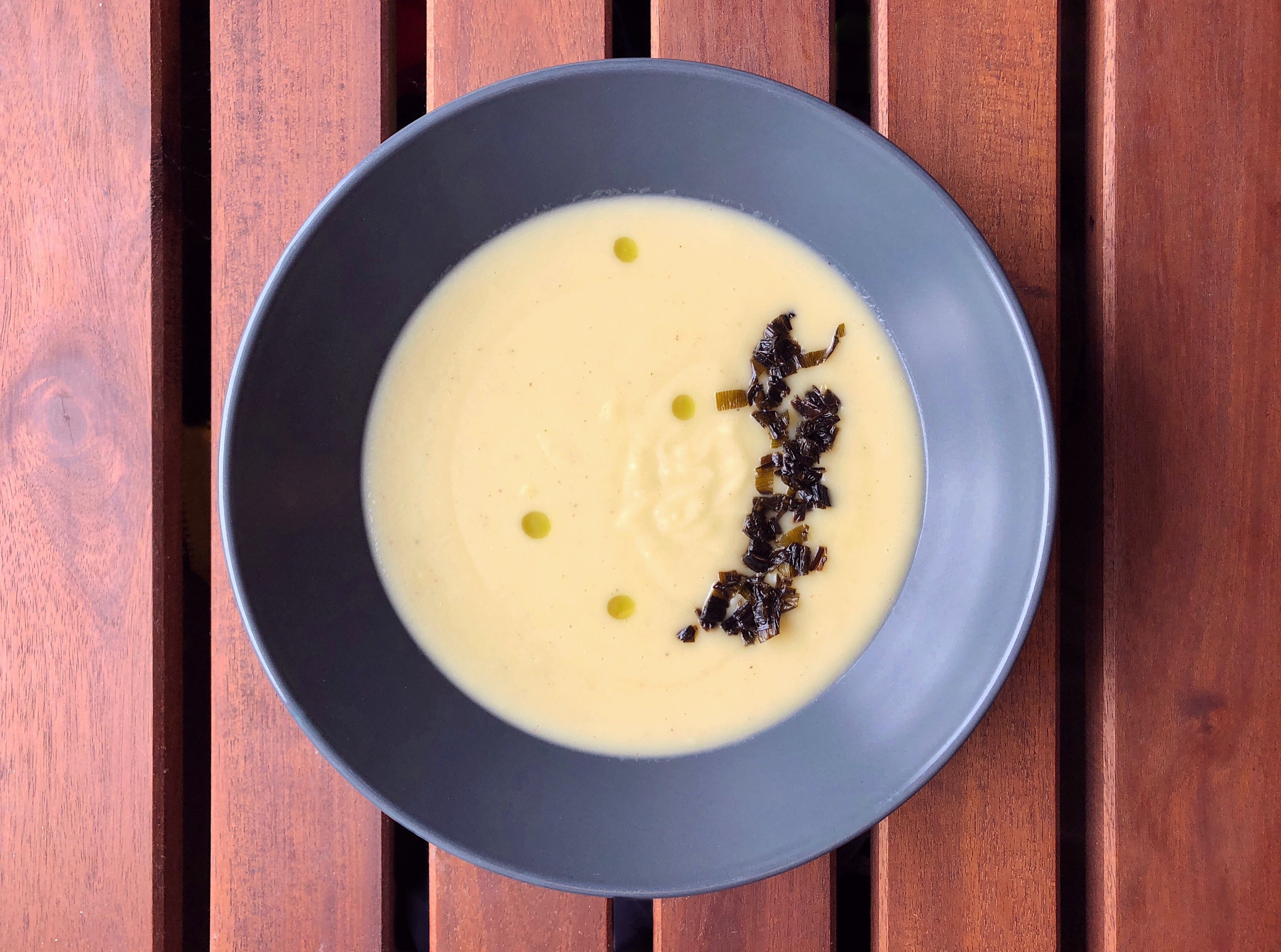 bowl of potato leek soup with crispy leek tops and leek oil