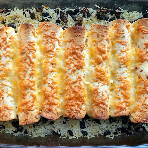 Enchiladas over rice and beans in a glass baking dish