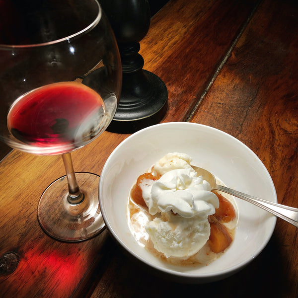 roasted peaches ofver ice cream, topped with chantilly cream, served with a glass of red wine